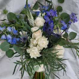Bouquet of white roses and blue flowers with greenery