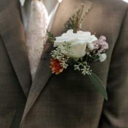 White rose boutonniere on a brown suit jacket