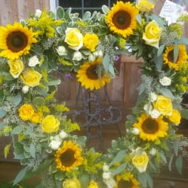 Sunflower and yellow rose wreath on a metal stand