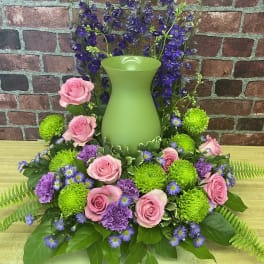 Pink roses and purple flowers arranged around a green vase