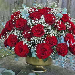 Red roses in a gold pedestal vase with baby's breath