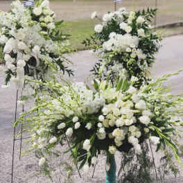White floral funeral sprays with lilies and roses on stands