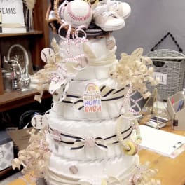 Diaper cake with baby shoes, baseballs, and ribbon decorations