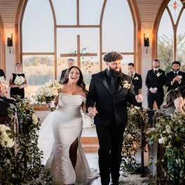 Bride and groom walking down the aisle with white floral arrangements