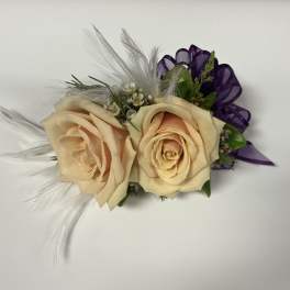Two cream roses with purple ribbon and white feathers