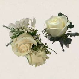 Ivory rose corsage with ribbon and matching boutonniere on a light background
