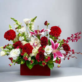 Mixed bouquet of red, white, and pink flowers in a red box