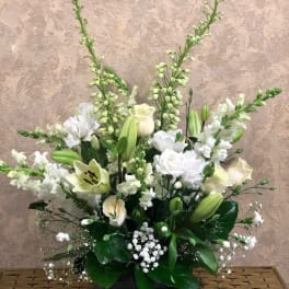 White floral arrangement in a black bowl vase with tall stems