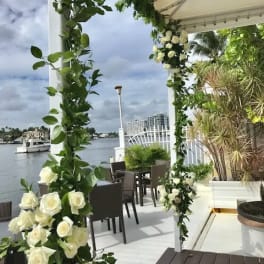 White rose floral arch on a waterfront patio