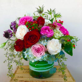 Bouquet of red, pink, and white roses in a green glass vase