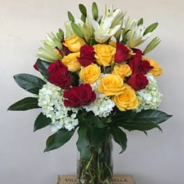Bouquet of red and yellow roses with white lilies in a glass vase