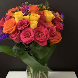 Bouquet of pink, orange, and yellow roses in a clear glass vase
