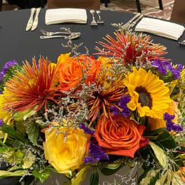 Bright mixed flower centerpiece with roses and sunflowers on a round table