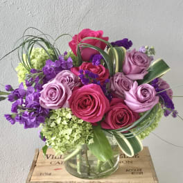 Bouquet of pink and lavender roses with purple flowers in a glass vase