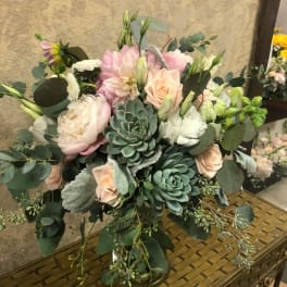 Bouquet of blush roses, pale pink blooms, and succulents in a glass vase