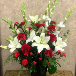 Red carnations and white lilies arranged in a black vase