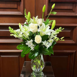 White lilies and roses in a clear glass vase