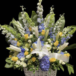 Basket arrangement of white lilies, yellow roses, and blue flowers with a Dad ribbon