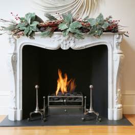 Holiday mantel garland with frosted leaves and red berries above a fireplace