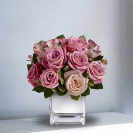 Pink and blush roses arranged in a clear square vase
