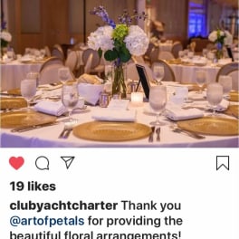 Round banquet table with a white floral centerpiece and gold chargers