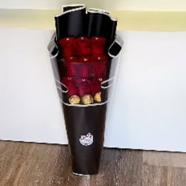 Bouquet of red roses wrapped in dark paper with gold accents
