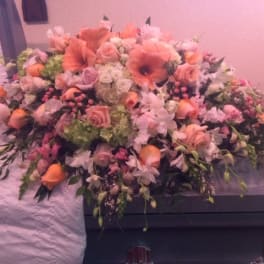 Large pink and peach floral casket spray with roses and lilies