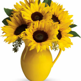 Yellow sunflowers arranged in a yellow pitcher vase