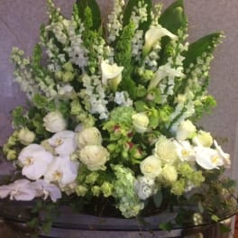 Large white and green floral arrangement with orchids and calla lilies