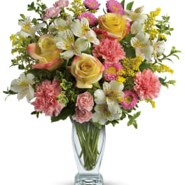 Mixed bouquet of roses, carnations, and white alstroemeria in a clear glass vase
