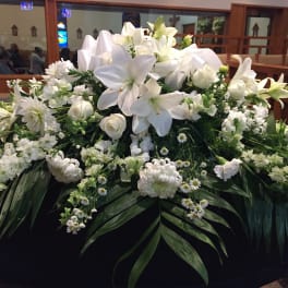 Large white floral arrangement with lilies and roses on a table