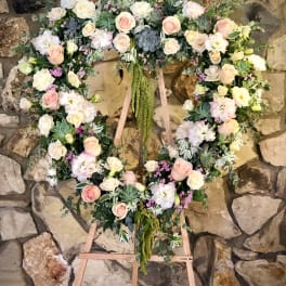 Heart-shaped floral wreath on a wooden easel with pink and white roses