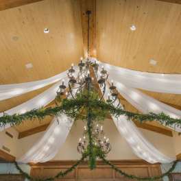 Chandelier draped with white fabric and greenery in a decorated hall