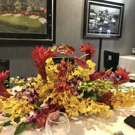 Low tropical centerpiece with red and yellow orchids on a table