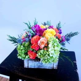 Colorful flower arrangement in a rustic white wooden box