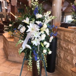 Tall white floral standing arrangement with blue accents on an easel
