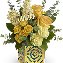 Yellow roses and cream carnations in a gold vase with a "thanks" sign