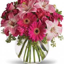 Pink lilies, gerbera daisies, roses, and carnations in a clear glass vase