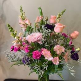 Mixed pink and purple flower arrangement in a clear glass vase