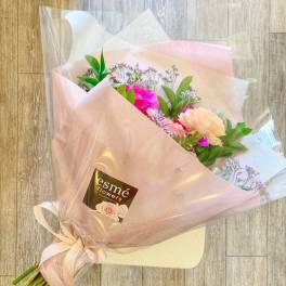 Pink and peach bouquet wrapped in translucent paper with a ribbon