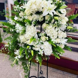 White floral standing spray with lilies, roses, and hydrangeas