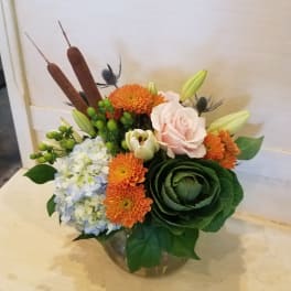 Mixed bouquet in a glass vase with orange and pale pink blooms