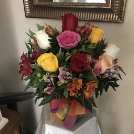 Mixed bouquet of roses and alstroemeria in a vase with a colorful ribbon