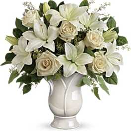 White lilies and cream roses arranged in a white vase