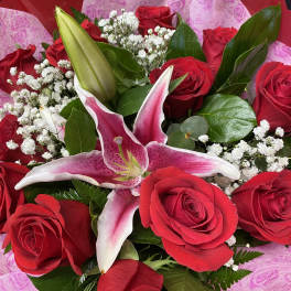 Bouquet of red roses and a pink lily with white filler flowers