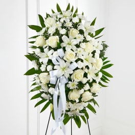 White floral standing spray with roses and lilies on a ribboned easel