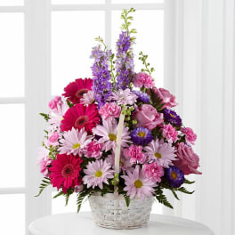 Pink and purple mixed flowers arranged in a white basket
