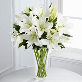 White lilies arranged in a clear glass vase
