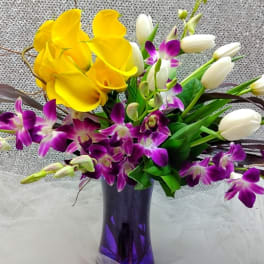 Yellow calla lilies and purple orchids in a purple vase