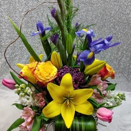 Tall mixed bouquet in a glass vase with yellow lilies and purple irises